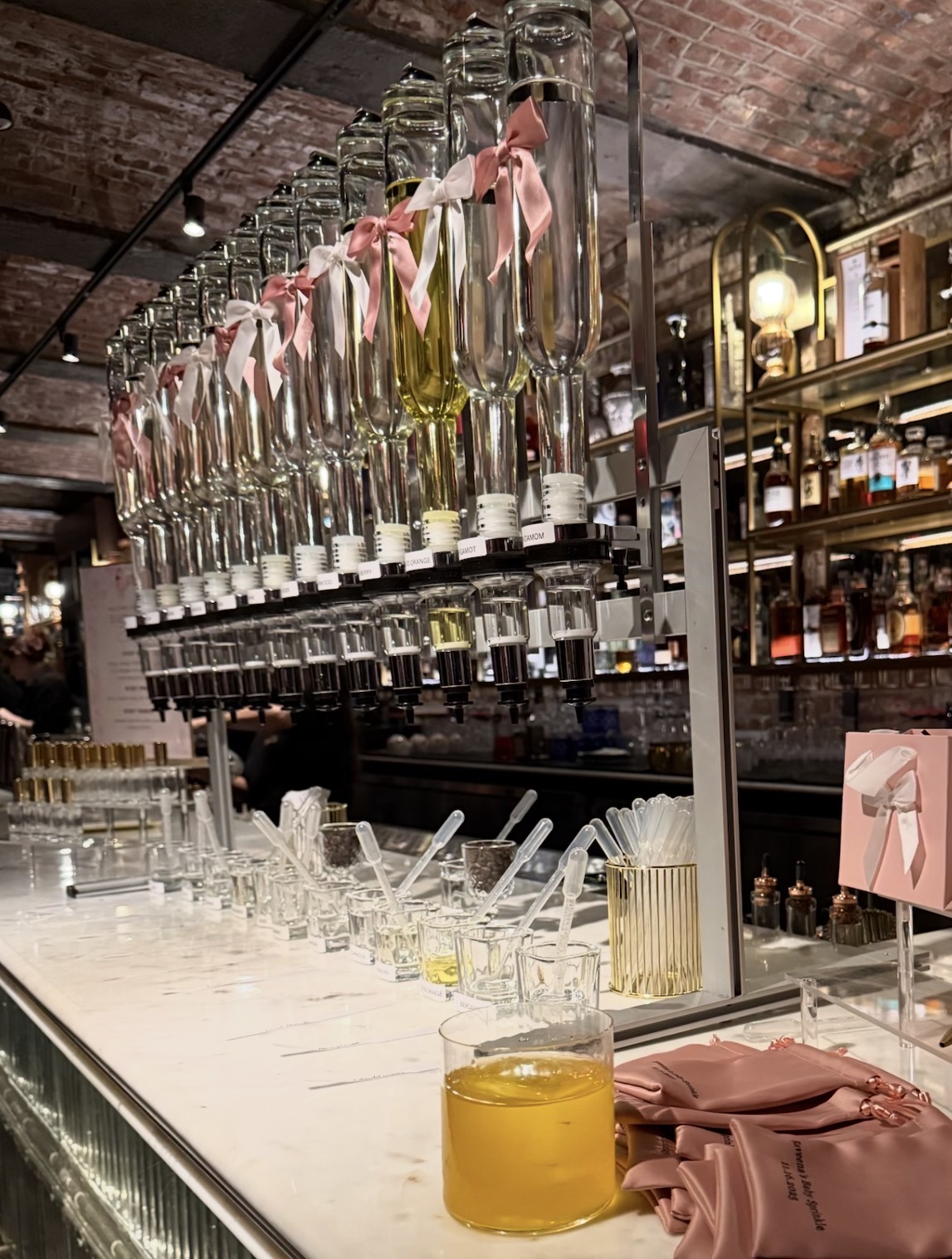 Custom fragrance bar with ribbon-tied ingredient bottles above a marble counter of mixing vials