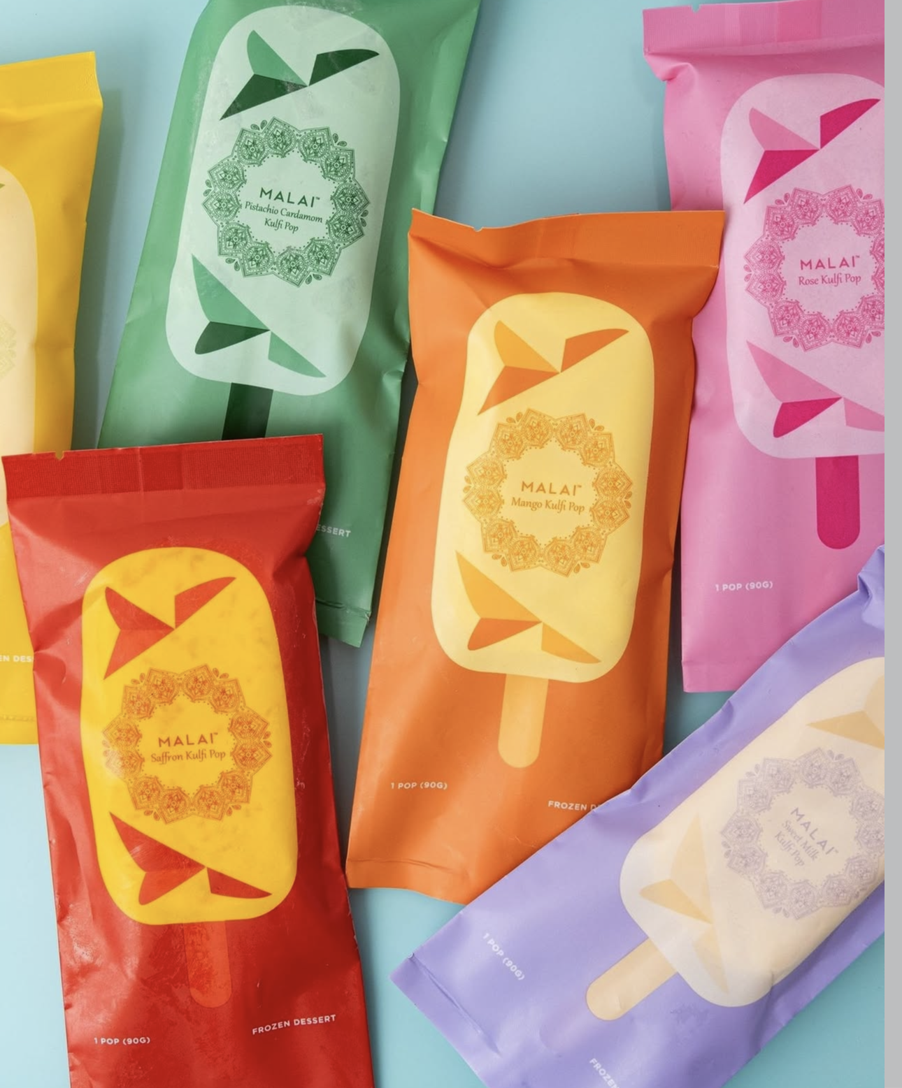 Colorful Malai kulfi pop wrappers arranged on a pale blue surface