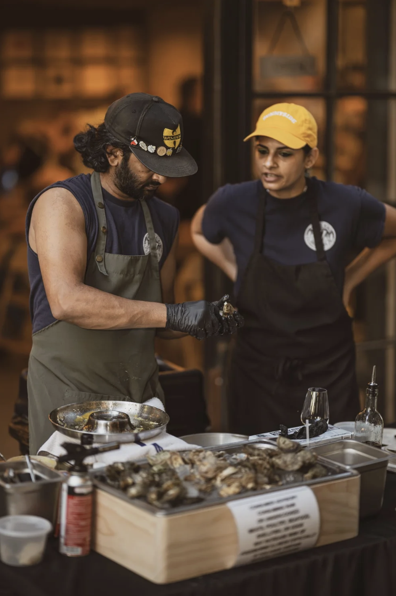 Hands shucking fresh oysters on linen